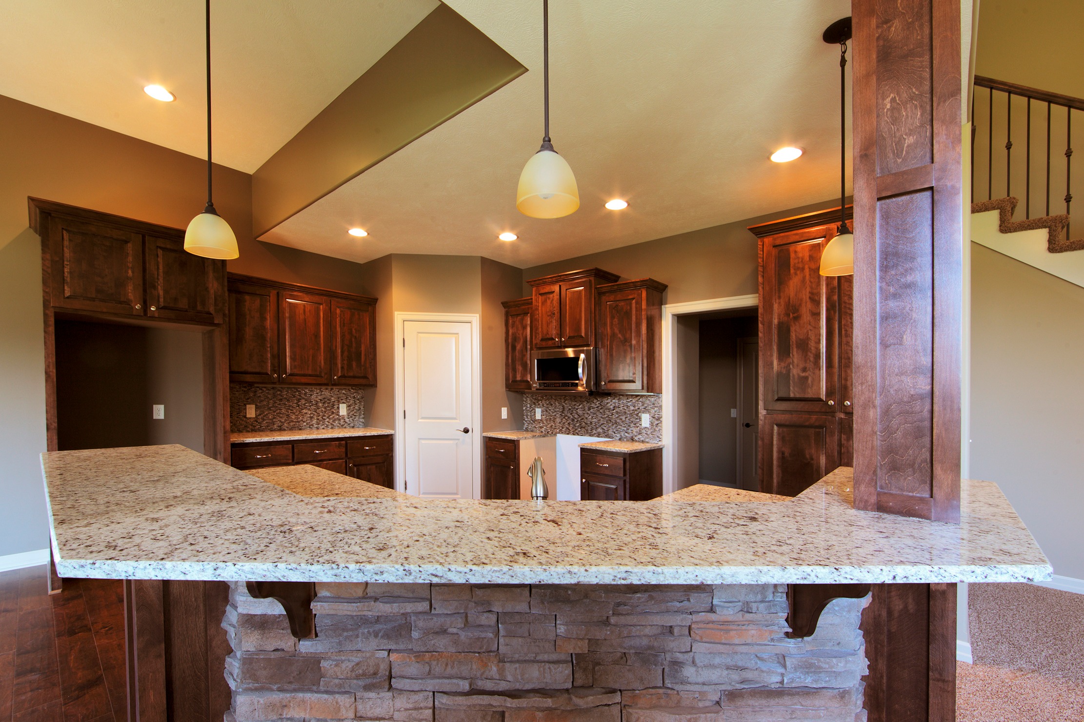 Custom dark cabinets with stone accent island and vaulted ceiling